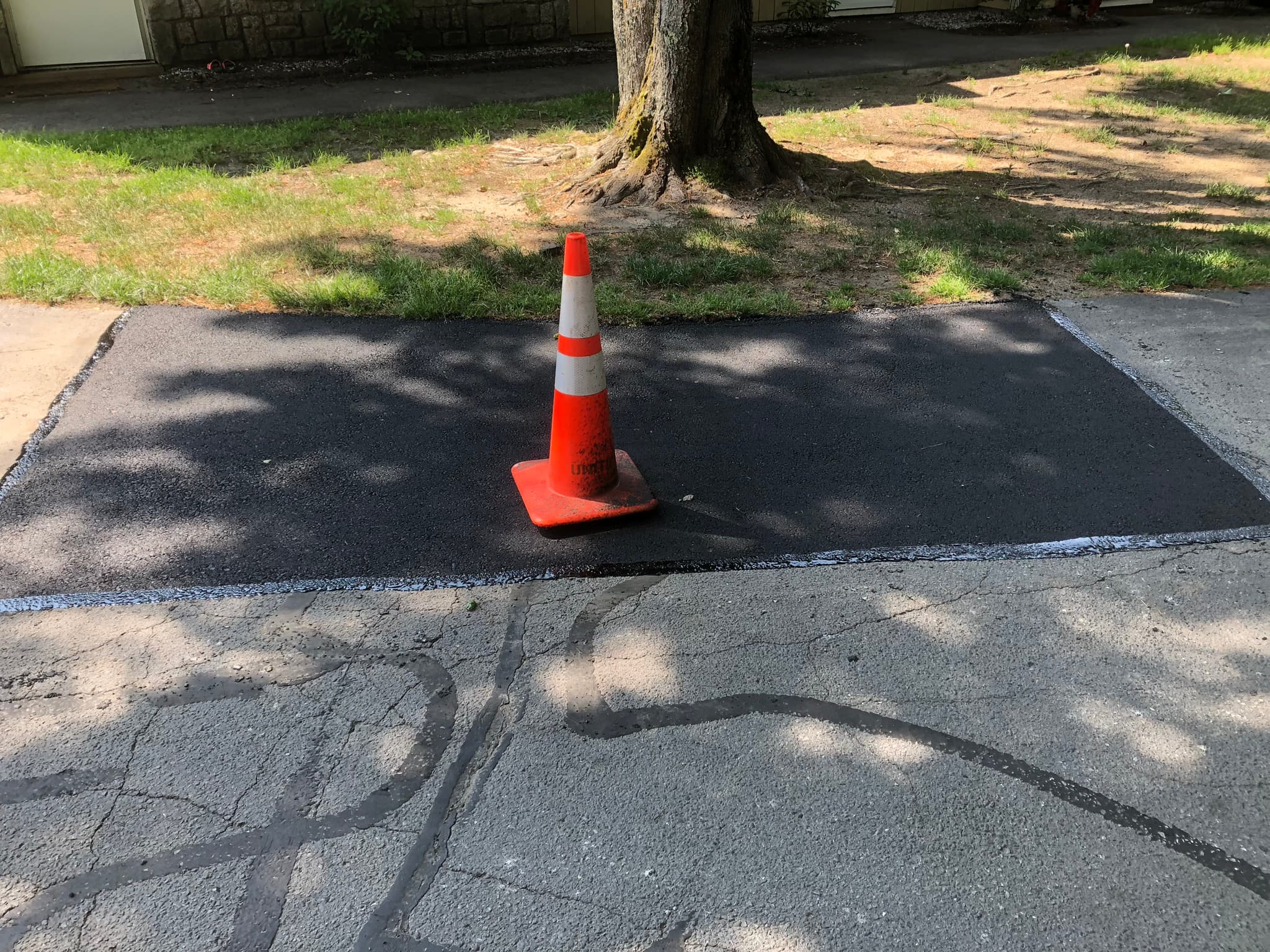 Hot-mix asphalt patch being compacted with a plate compactor, year-round repair work