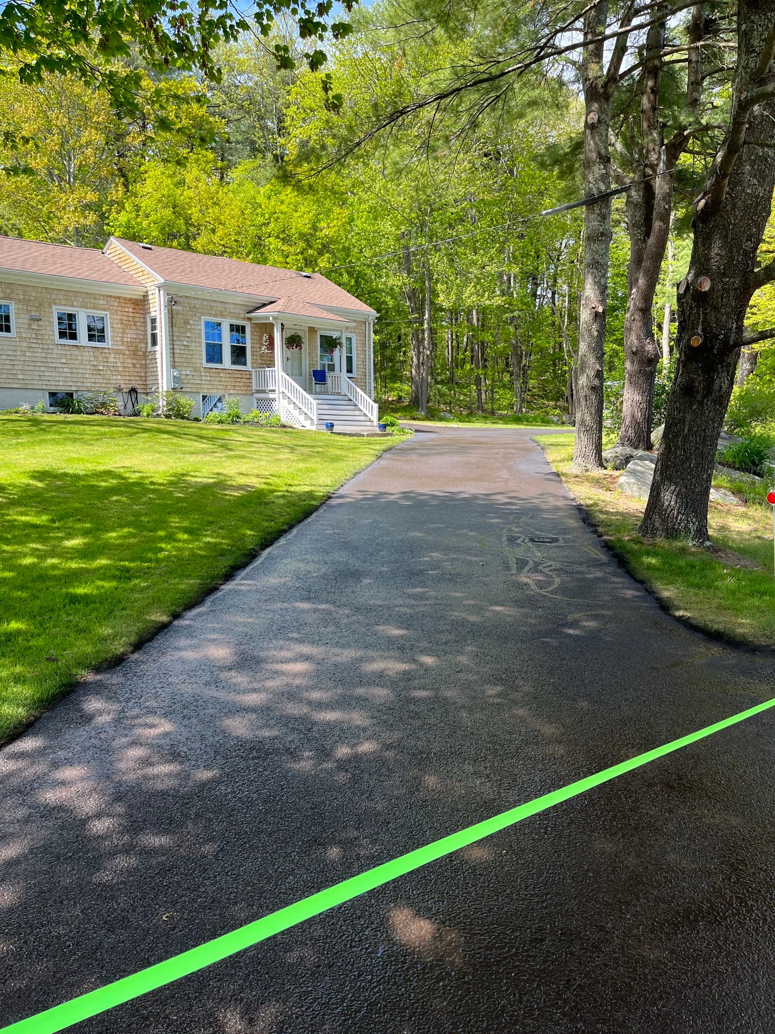 Long narrow driveway between houses, fresh sealcoat with clean edges on both sides