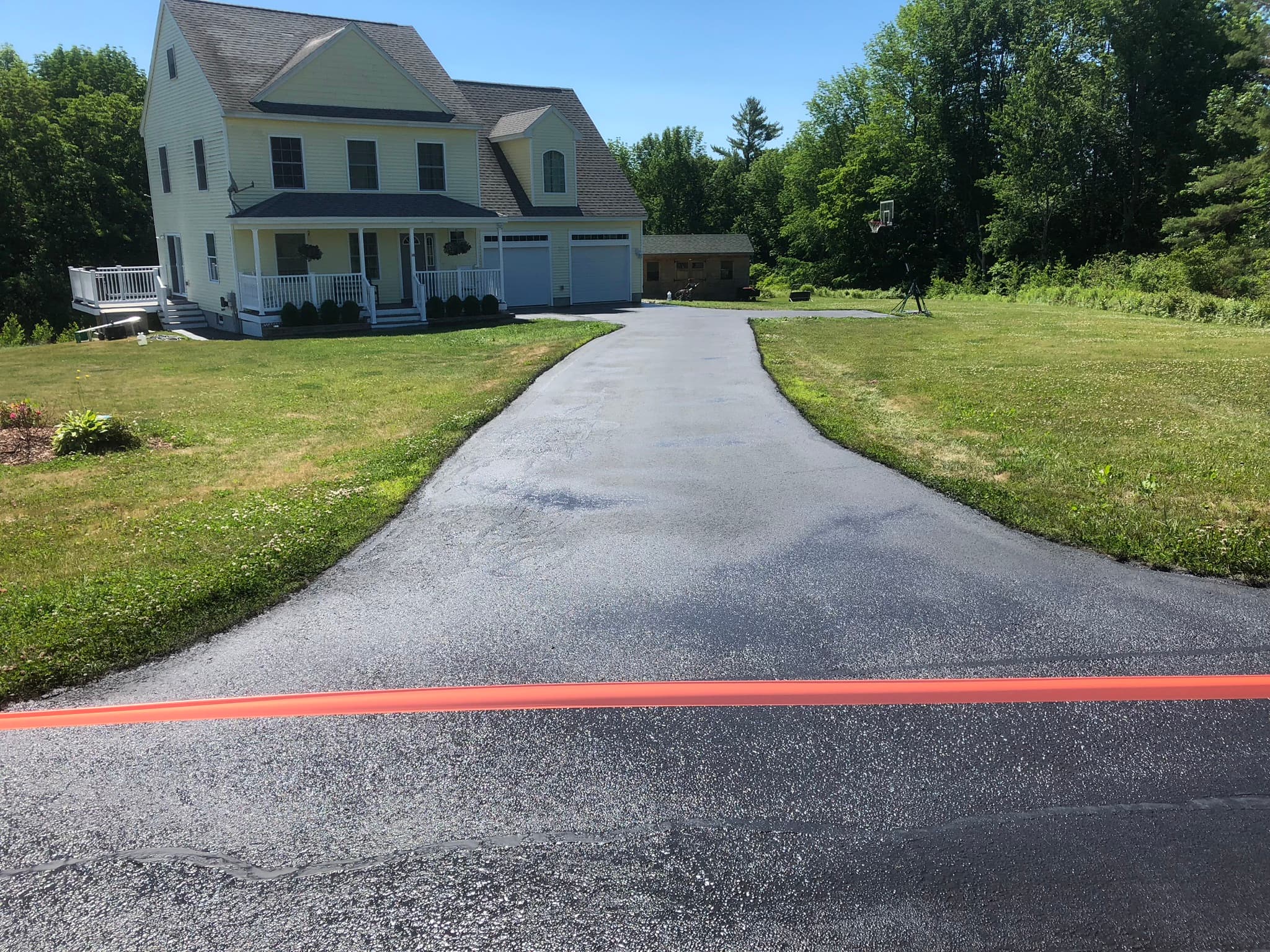 Large flat driveway with landscaping border, fresh sealcoat, sharp edge work