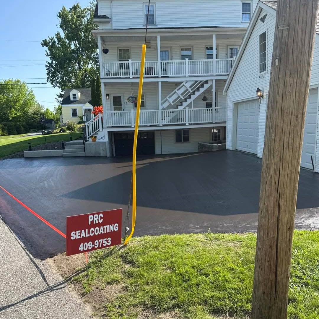 Large multi-story home with wide courtyard driveway, freshly sealed and staked off to cure