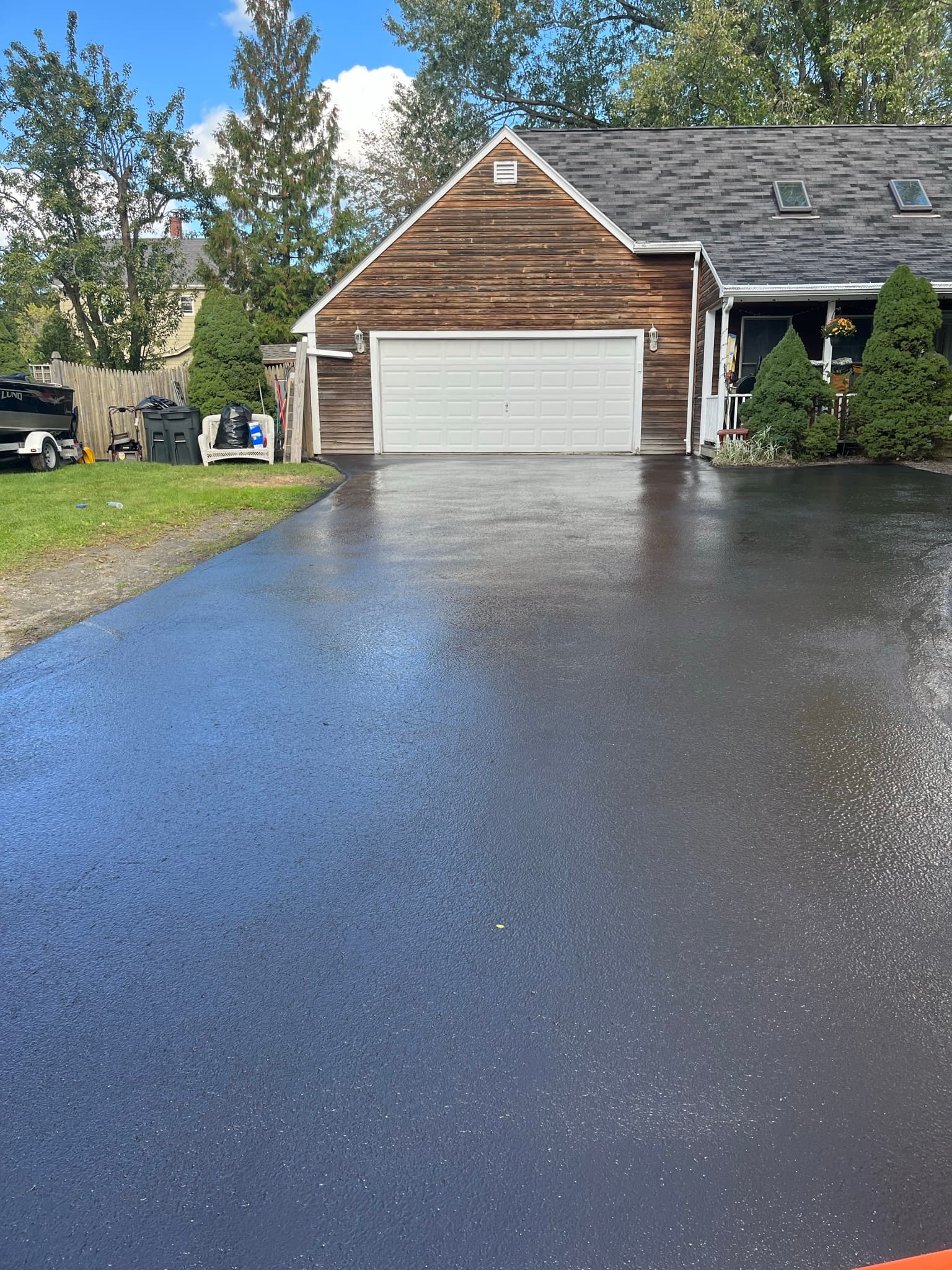 Freshly sealed residential driveway with new construction home in background