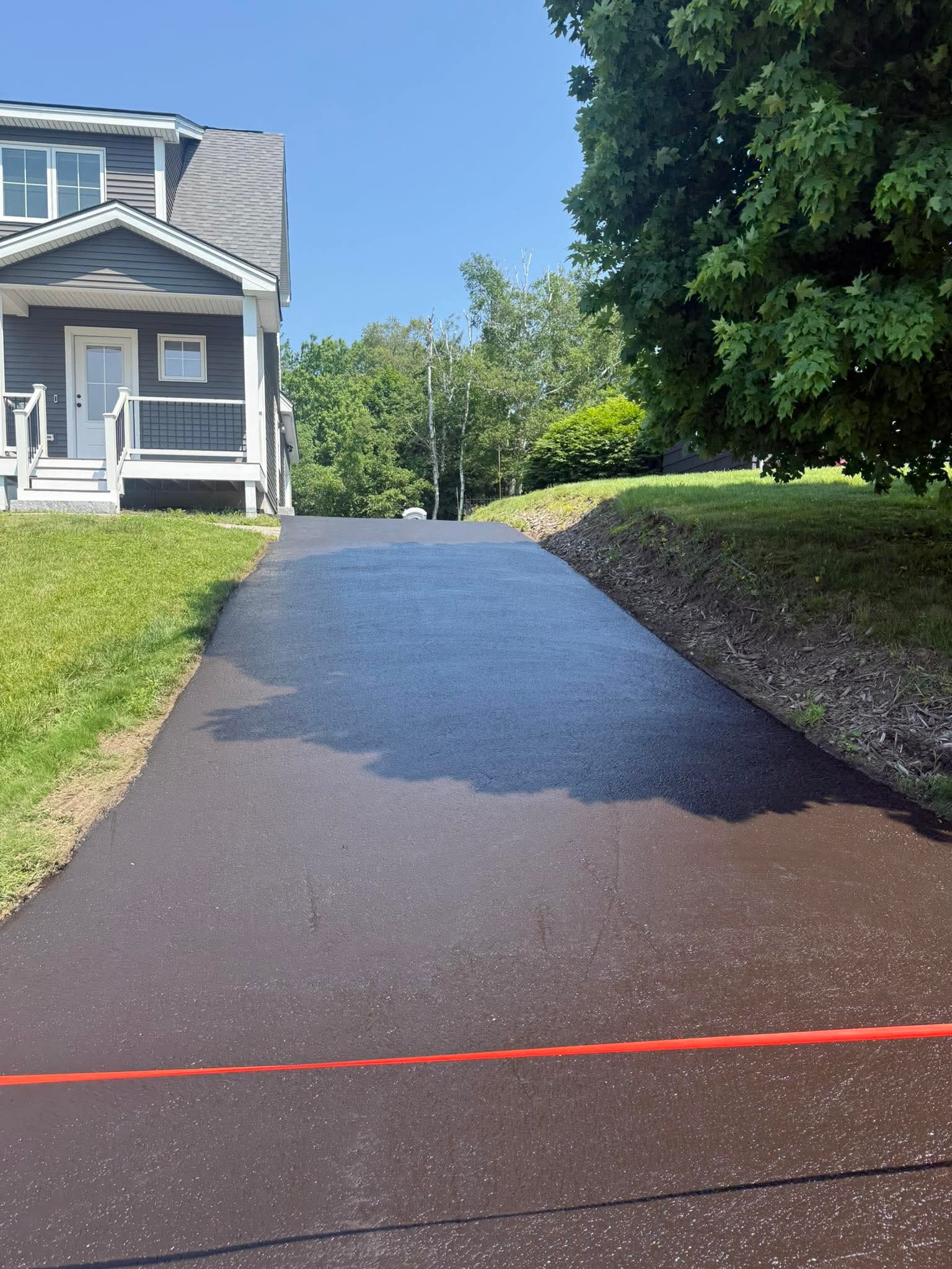 Fresh sealcoat on a hillside residential driveway, clean edges, uniform coverage